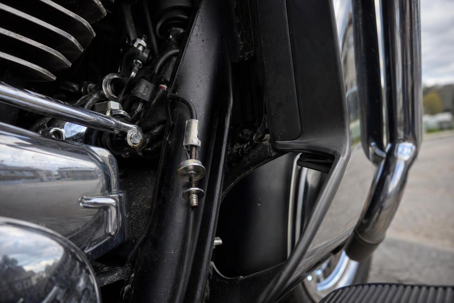 the left-side deflector mounting area with the cable clamp, washer and screw positioned on the cruise-control cable before the U clip is fitted