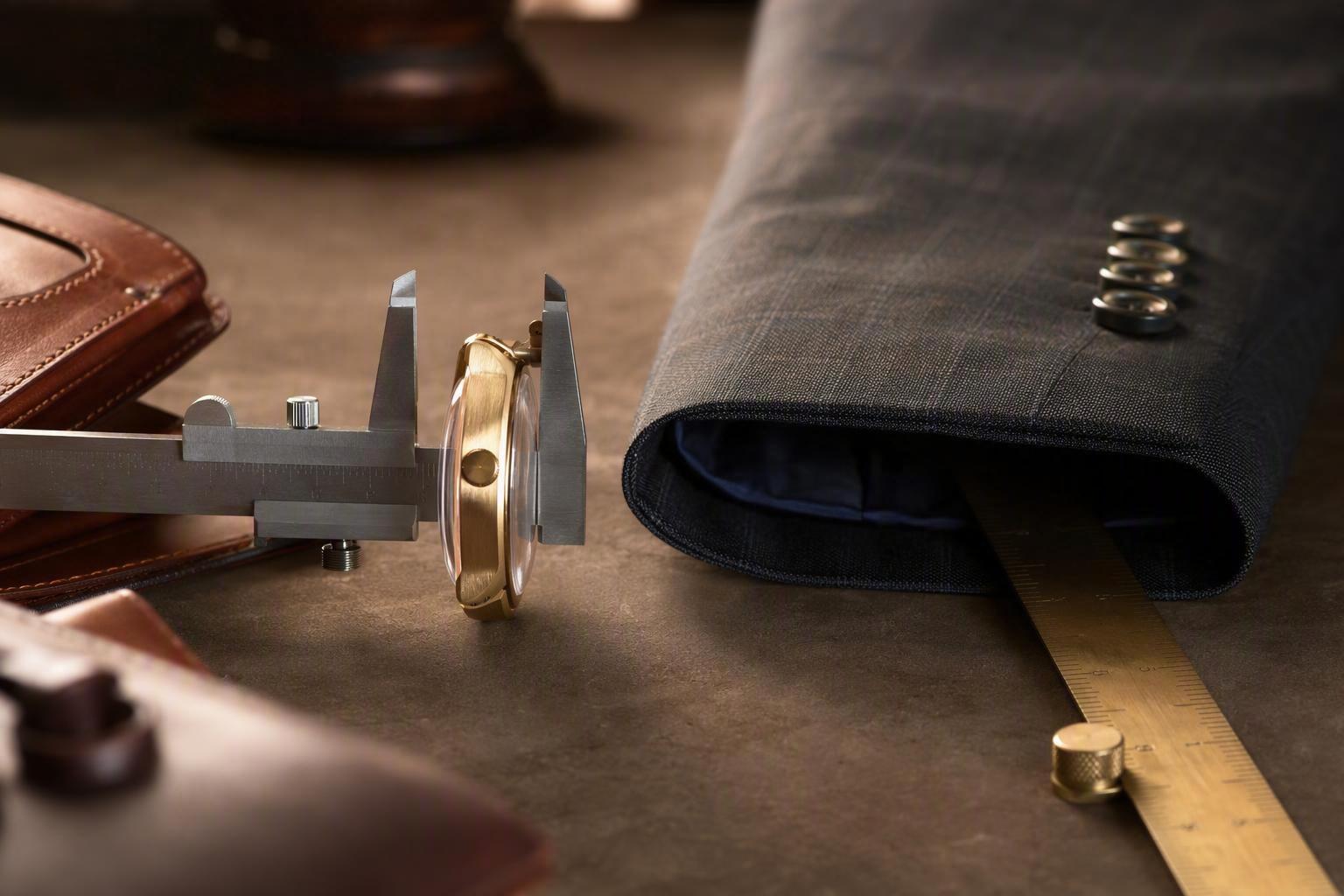 calipers or a ruler across a watch case profile beside a cuff opening measured flat